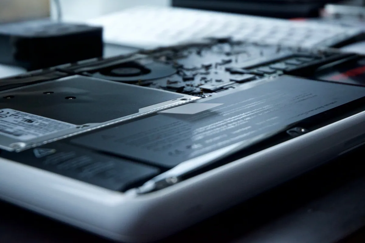 Laptop with its base removed, showing the hard drive, battery and cooling fan inside