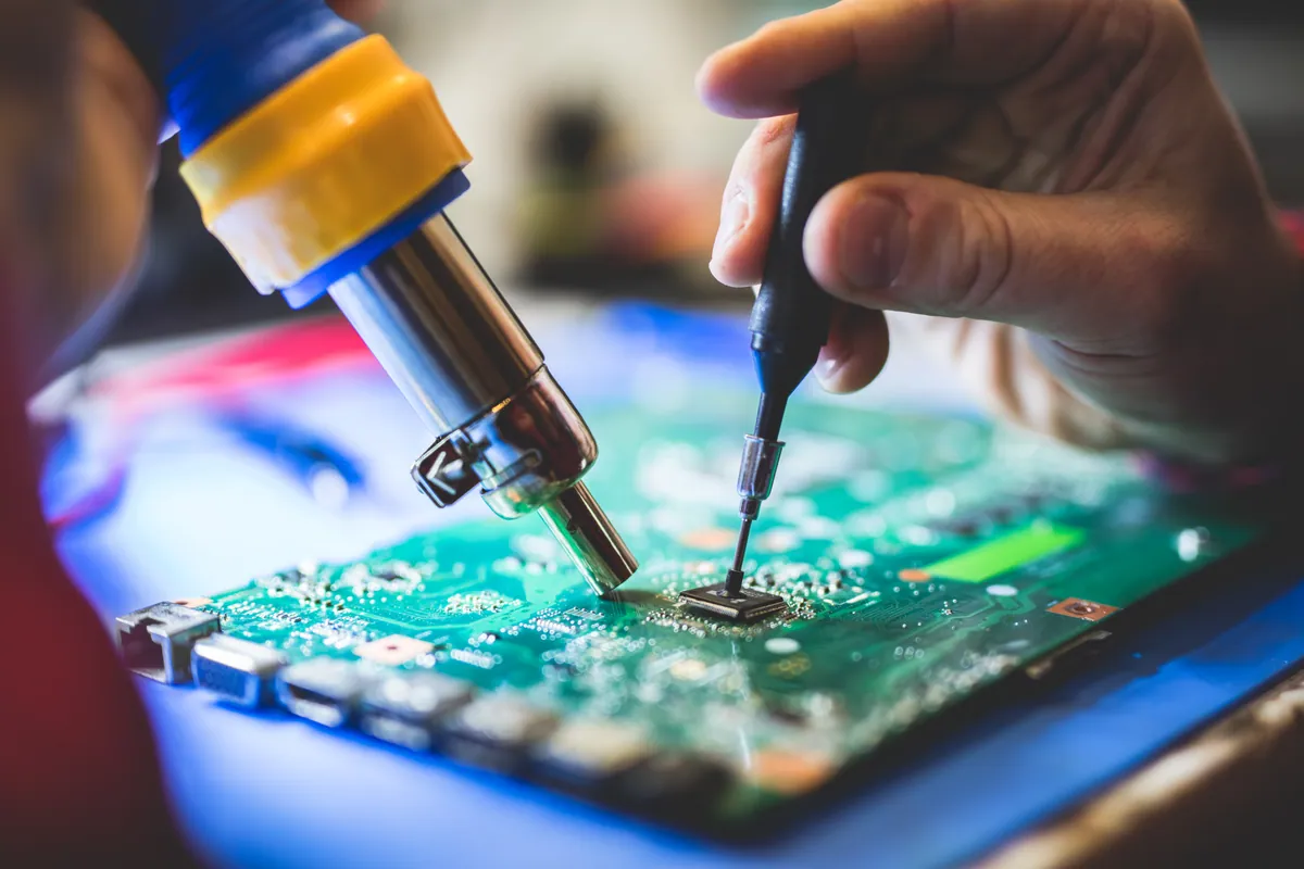 Close-up of a circuit board being worked on with a fine-tip soldering iron